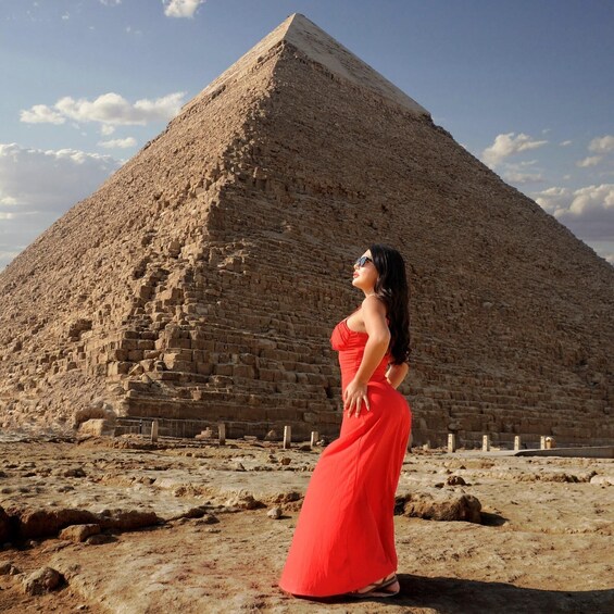 A person in a red dress standing in front of a pyramid. 3