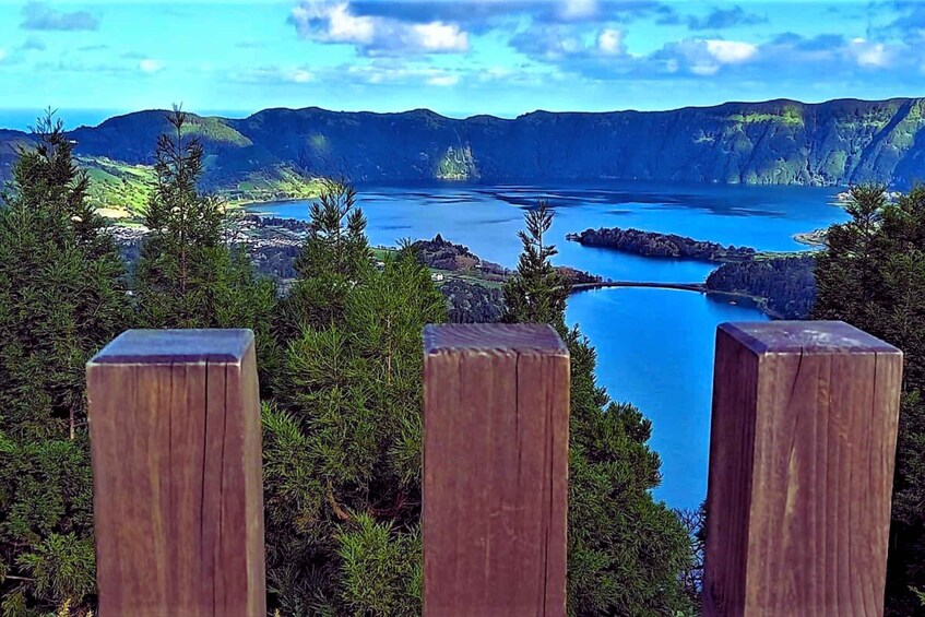 A coastal landscape with a clear view of the sea, surrounded by dense green forest and rocky outcrops. 1