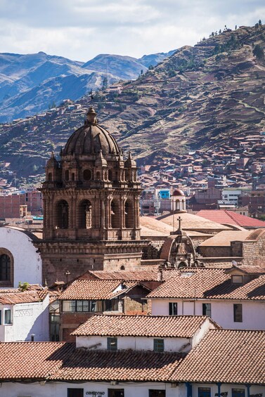 A historic church with a dome, surrounded by terraced houses and mountains in the background. 3