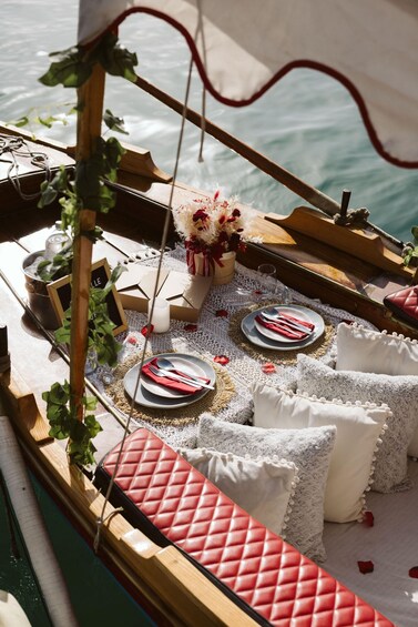 A boat with a table set for a meal, surrounded by pillows and a vase with flowers. 5