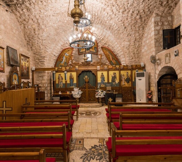 An interior of a church with wooden pews, a central altar, and religious paintings on the walls. 5