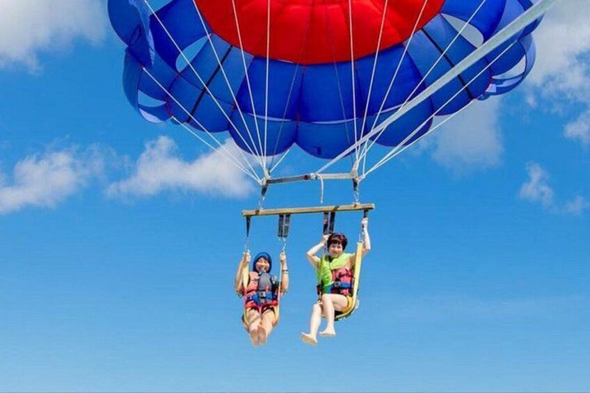 Two people skydiving with parachutes against a clear blue sky. 5