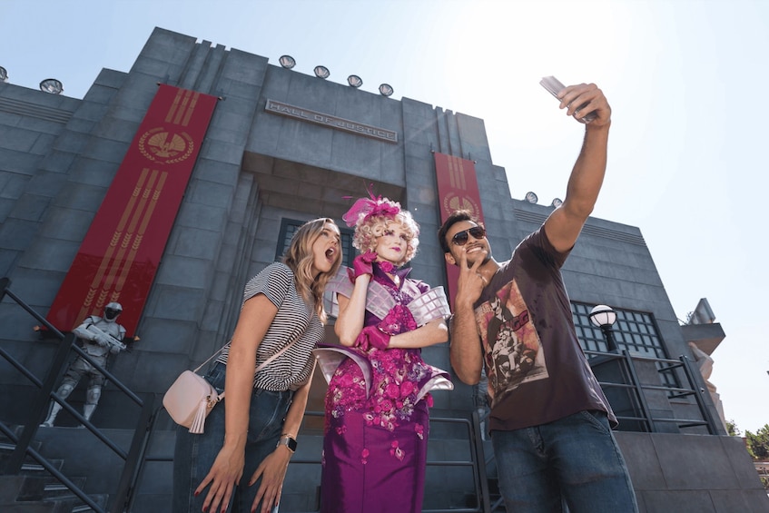 Menschen machen ein Selfie vor einem Gebäude mit einem großen roten Banner und einem Schild, auf dem 'Hall of Justice' steht. 2