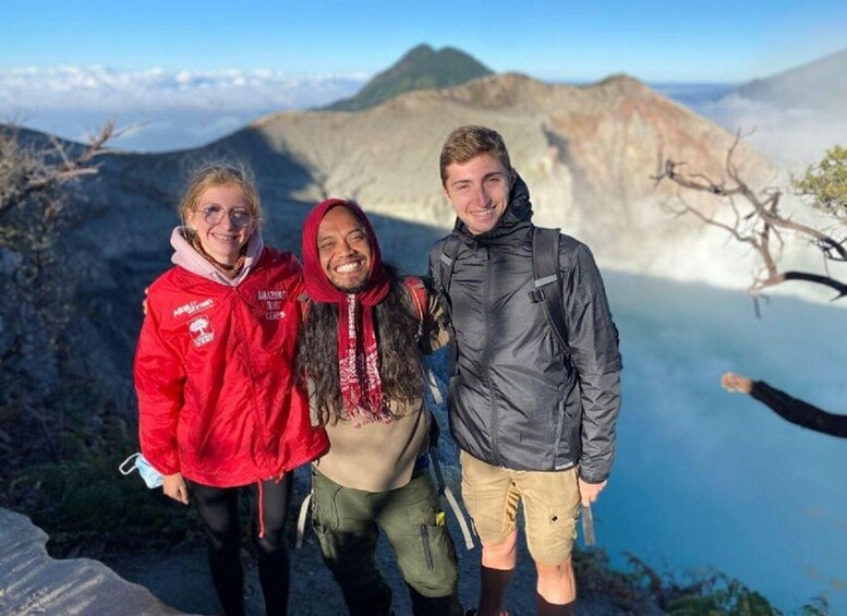 Three people standing on a mountain edge with a glacier in the background. 5