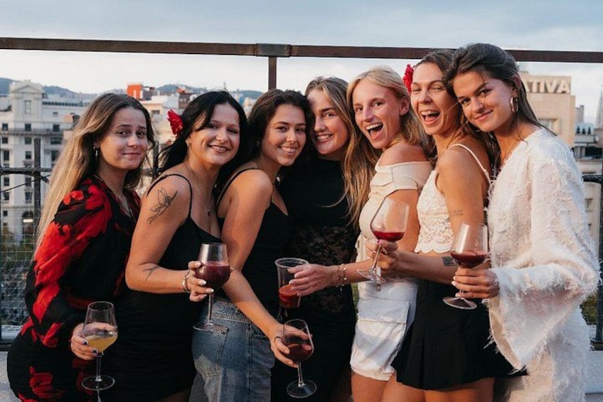 A group of people standing on a rooftop terrace, holding wine glasses. 2