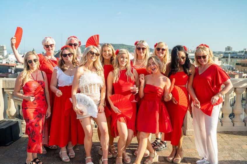 A group of people on a rooftop, some holding red fans. 1