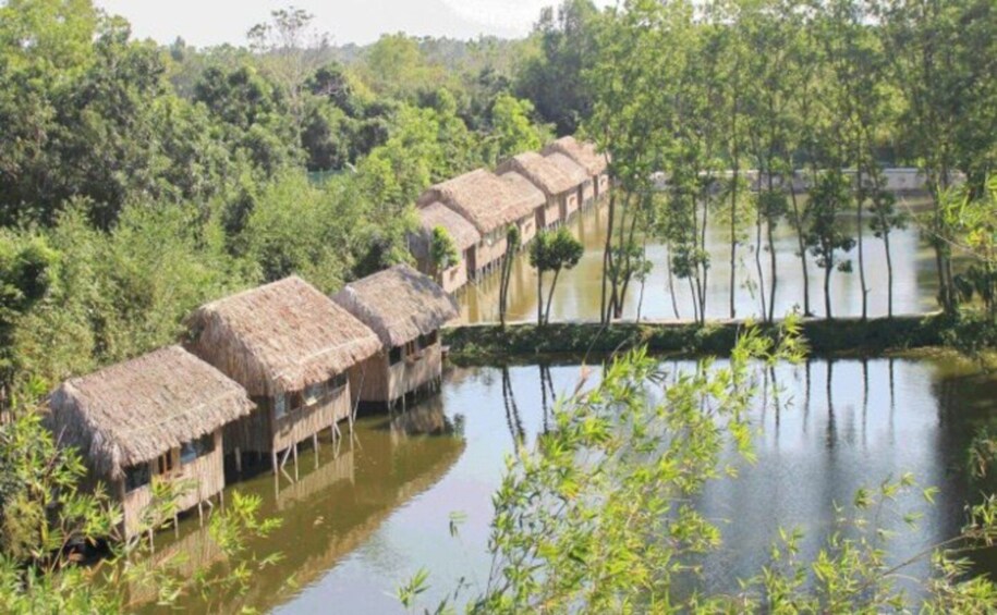 Thatched-roof huts on stilts in a water body surrounded by dense greenery. 4