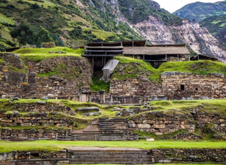 Ancient stone ruins with a wooden structure on a hillside. 1