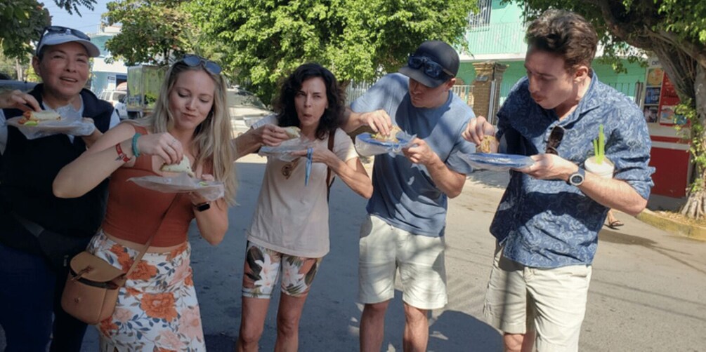 A group of people eating at an outdoor food stall. 2