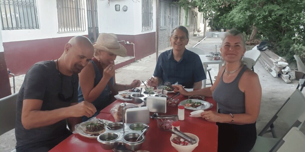 A group of people dining outdoors at a table with various dishes and utensils. 3