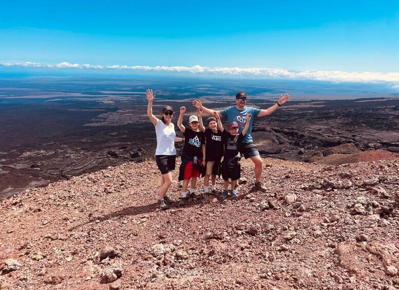 A group of people standing on a rocky terrain with a vast landscape in the background. 4