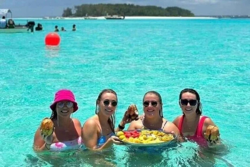 A group of people in a clear blue sea, holding a plate of food. 5