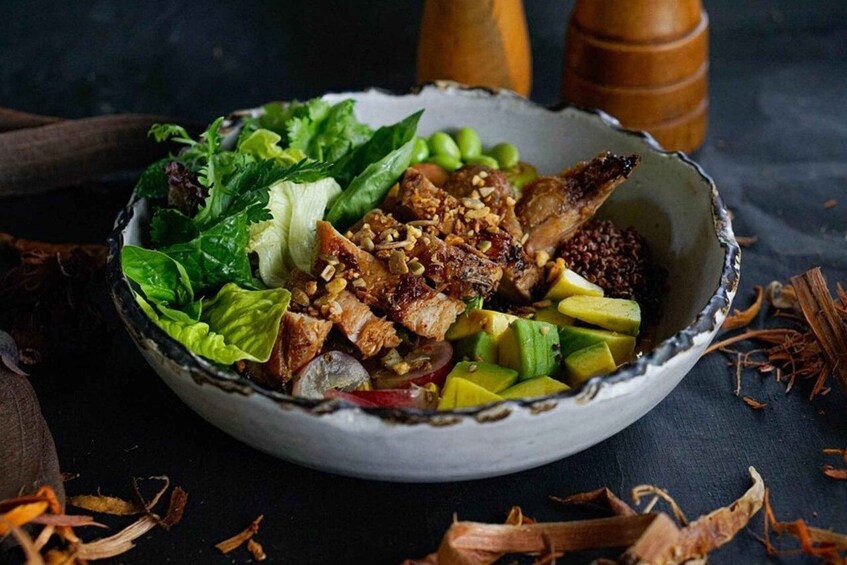 A bowl of salad with lettuce, avocado, and grilled meat. 3