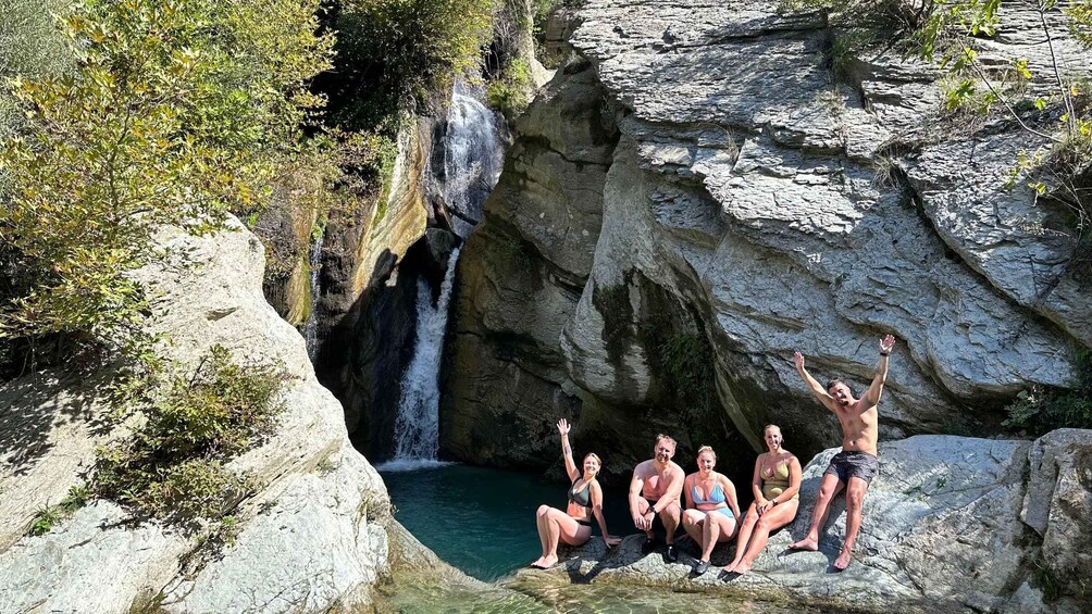 A group of people sitting on rocks by a waterfall. 1