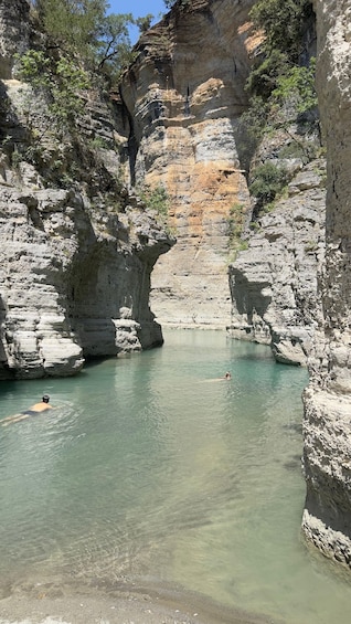A natural pool surrounded by rocky cliffs with clear water. 4