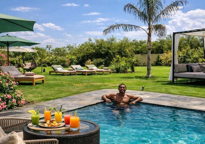 A swimming pool with lounge chairs and a table with drinks. 3