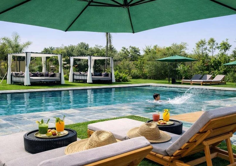 A poolside with lounge chairs, umbrellas, and a person swimming. 5