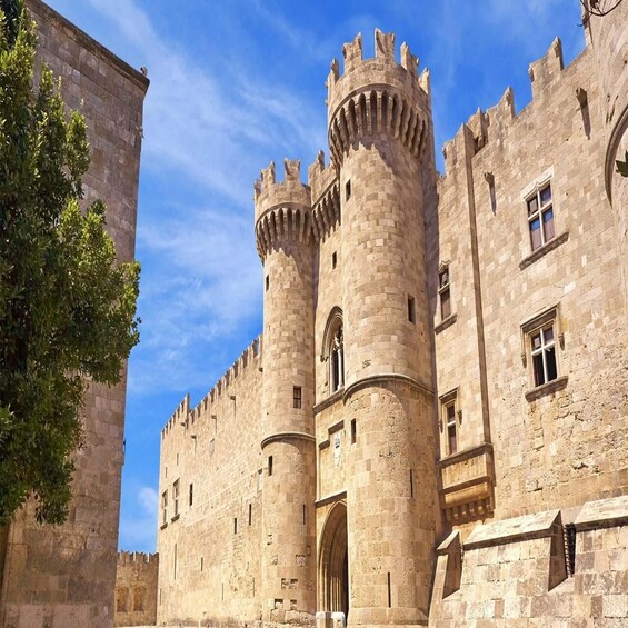 A medieval castle with two prominent towers, a large arched entrance, and a stone wall. 2