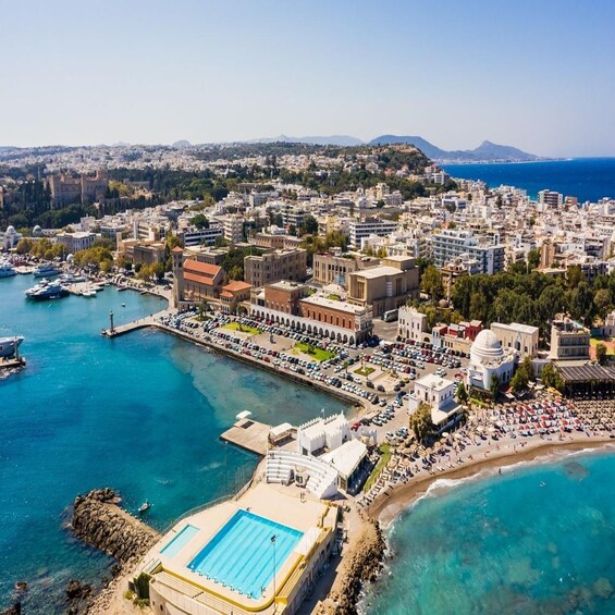 An aerial view of a coastal city with a marina, a large swimming pool, and a densely built urban area with historical architecture. 4