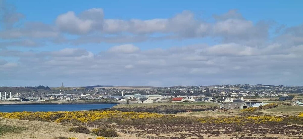 A coastal town with a large body of water, sandy dunes, and a clear sky. 2
