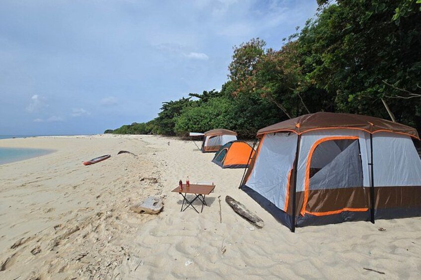 A sandy beach with tents and a boat. 4