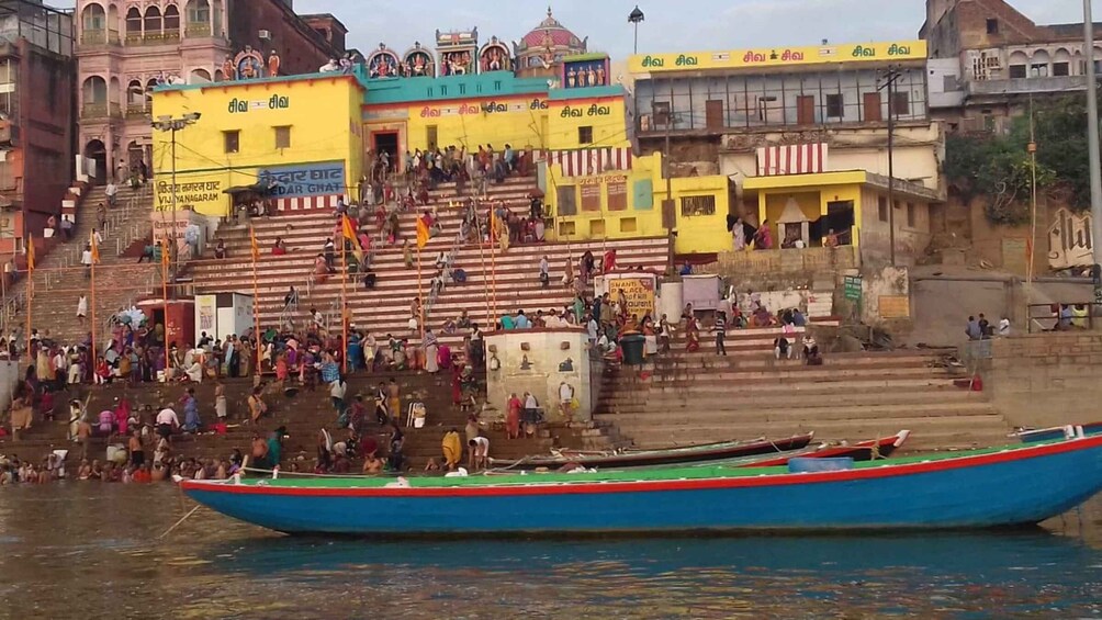 A crowded riverside with a colorful boat in the foreground. 5