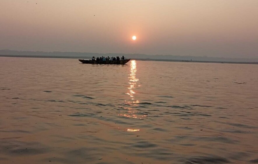 A calm body of water with a boat carrying people, reflecting the sun, and a distant shoreline. 4