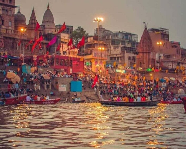 A river with boats, a crowd on the riverbank, and buildings in the background. 3