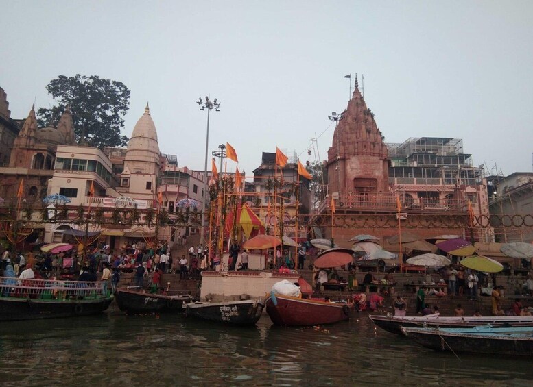 A riverside with boats, a temple, and a crowd of people. 2