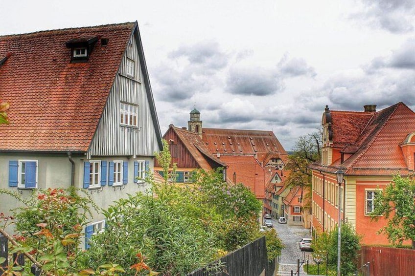 Een smalle straat met traditionele Europese huizen, een geplaveid weggetje en weelderige begroeiing. 1