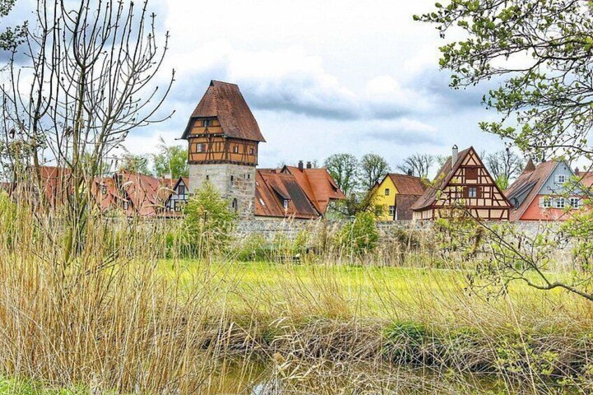 Een dorp met traditionele vakwerkhuizen, een opvallende toren en een gazon op de voorgrond. 2