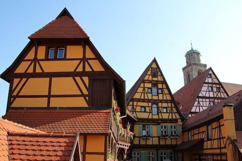 Traditional half-timbered houses with a prominent tower in the background. 1