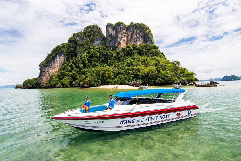 A speedboat named "WANG SAI" on clear water with a large island in the background. 1