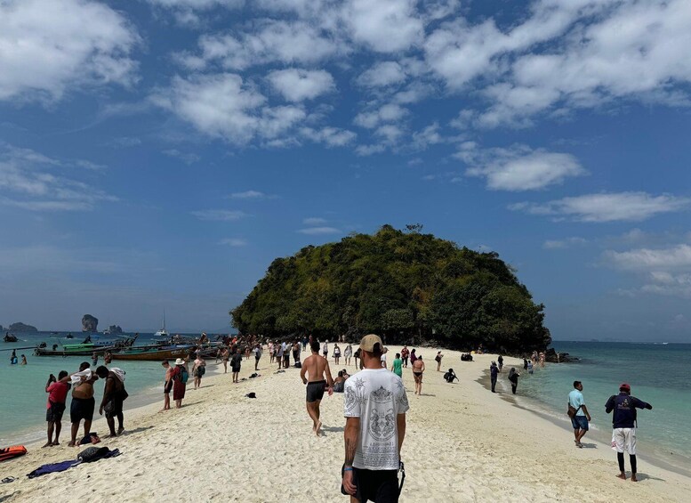 A beach with people walking and boats in the water. 4