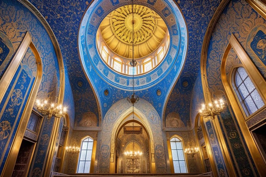 A grand hall with intricate blue and gold ceiling designs, a large central dome, and arched windows. 3
