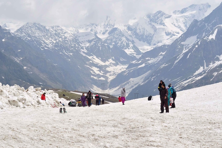 A group of people on a snowy mountain with snow-covered peaks in the background. 3