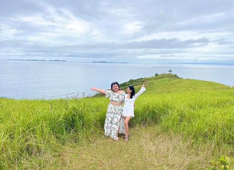 Two people standing on a grassy hill overlooking a body of water. 4