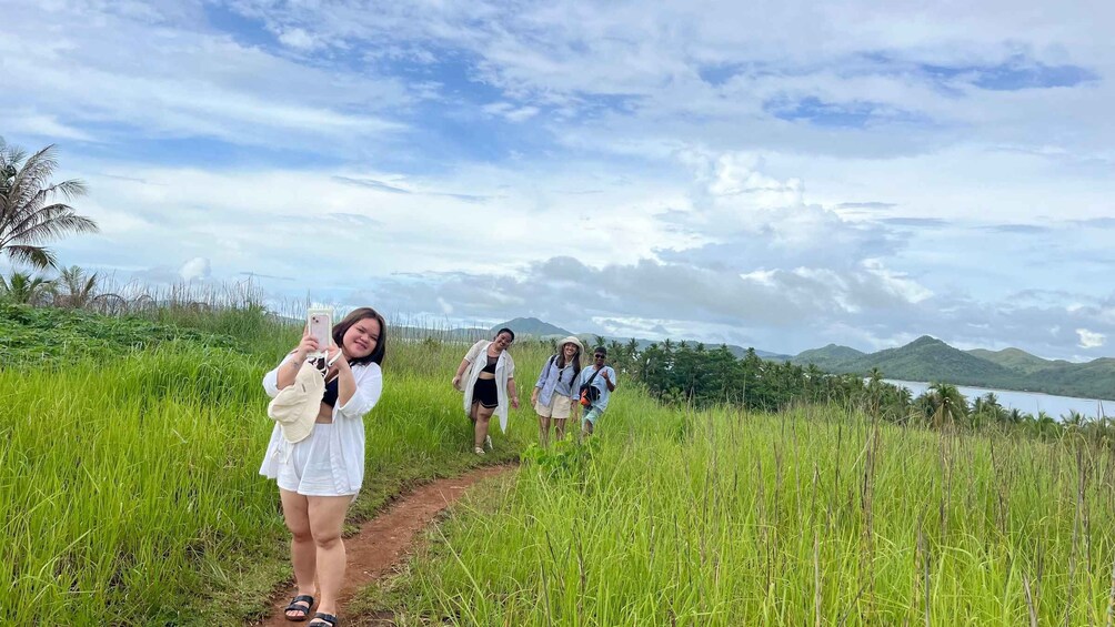 A group of people walking on a grassy path with a lake and mountains in the background. 2