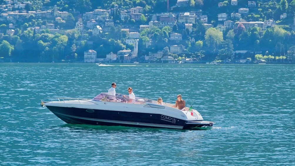 A speedboat with passengers on a calm lake with a cityscape in the background. 3