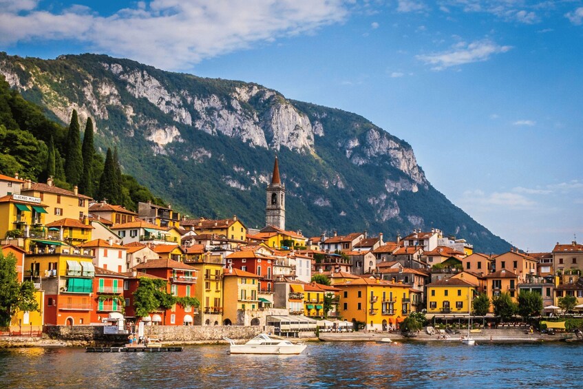 A coastal town with colorful buildings, a church tower, and a mountain in the background. 5