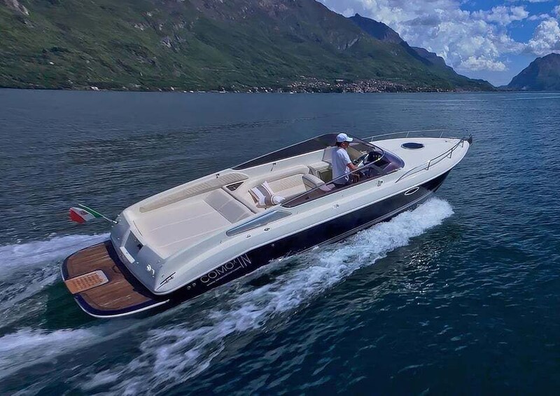 A speedboat on a calm lake with mountains in the background. 2