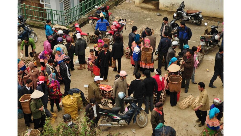 A crowded outdoor market with people carrying baskets and goods. 3