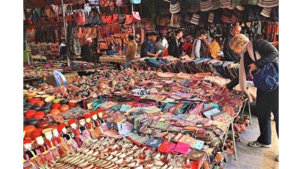 A bustling market with various stalls selling textiles, bags, and other goods. 4