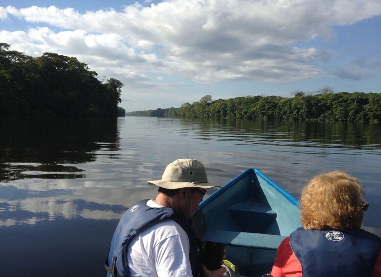 Two people on a boat on a calm river surrounded by dense forest. 5