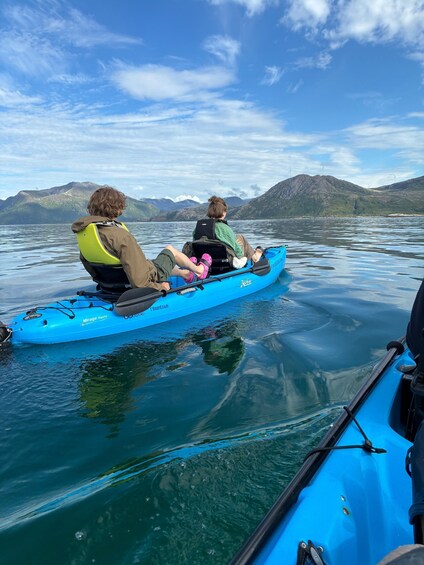 Two people kayaking on a calm lake with mountains in the background. 2