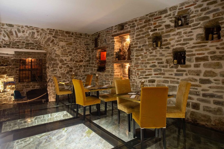 A dining area with stone walls, a glass table, and yellow chairs. 2