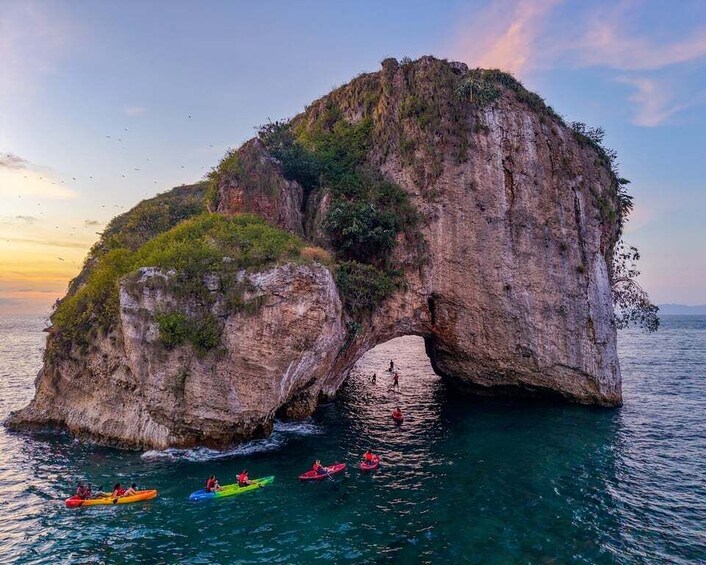 A natural rock arch formation with kayaks in the water below. 2