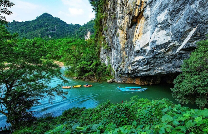 A river with kayaks, surrounded by lush greenery and a rocky cliff. 1