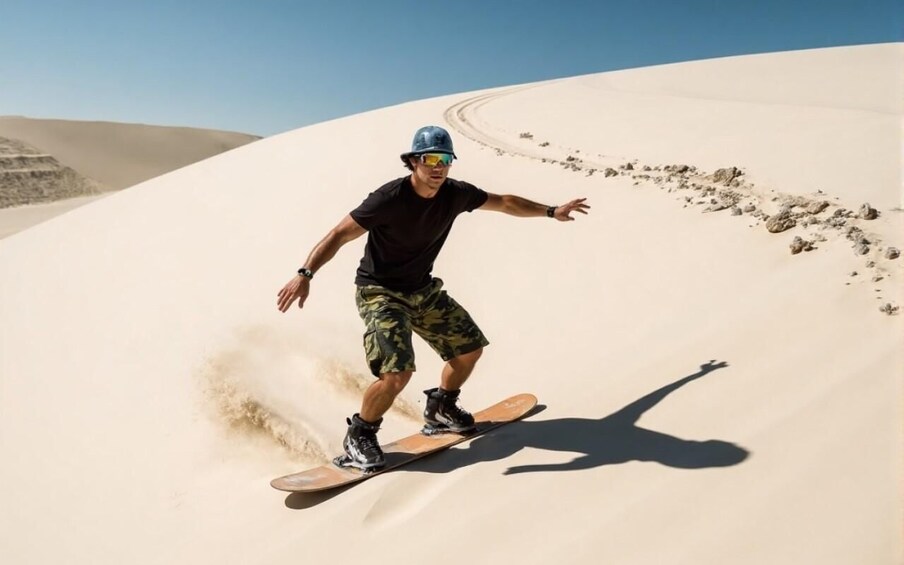 A person snowboarding down a sandy dune. 3