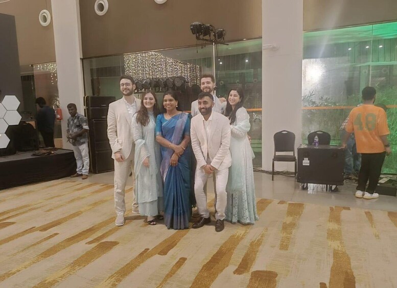 A group of people posing for a photo in a modern indoor setting with a patterned carpet and decorative lighting. 2